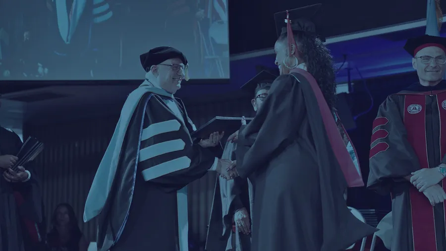 El presidente de la Facultad entrega un diploma durante la ceremonia de graduación